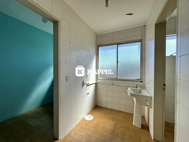 Banheiro com revestimento de azulejos brancos e piso de cerâmica.