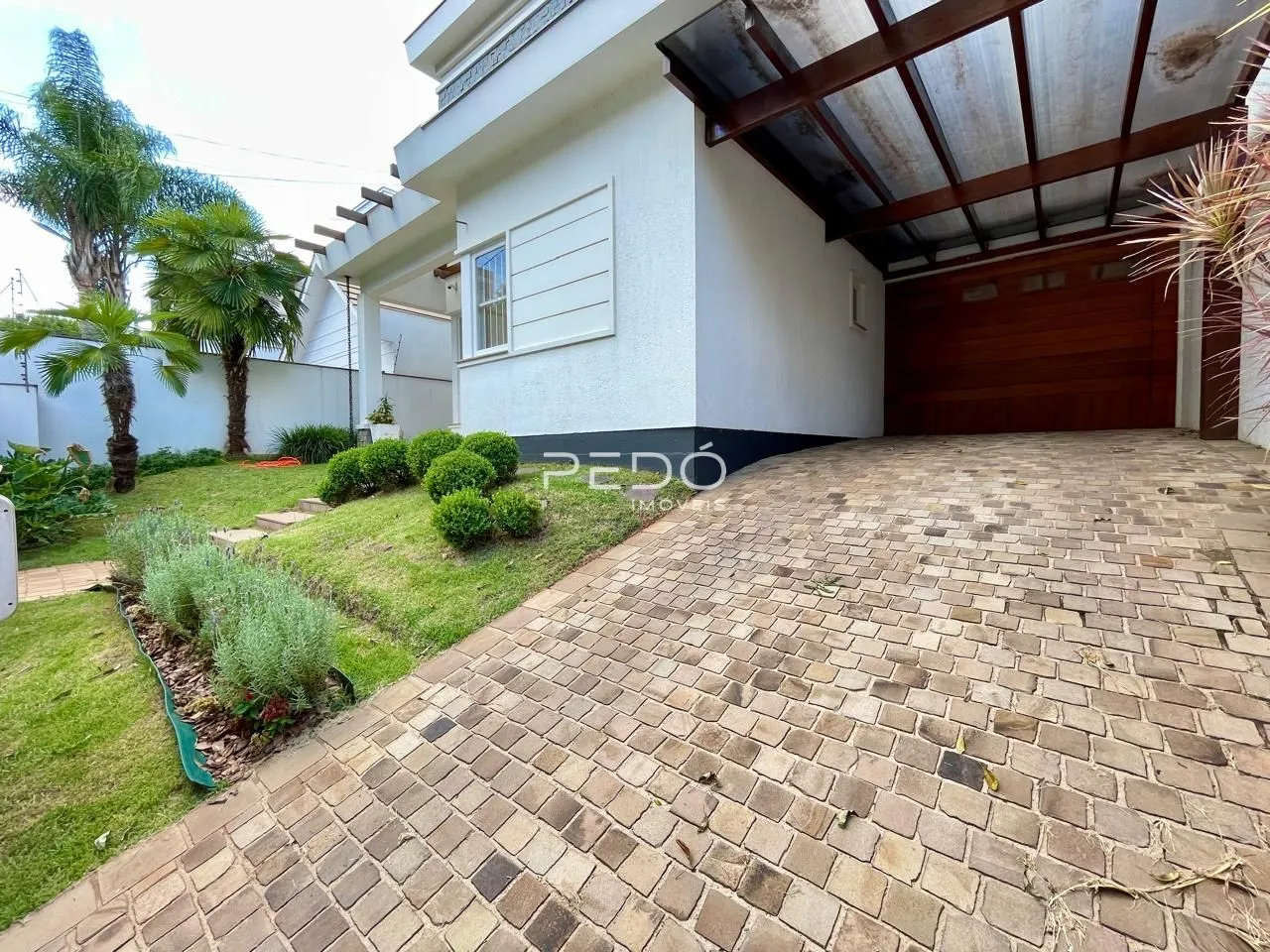 Vista da fachada de uma casa com jardim e calçada de tijolos.