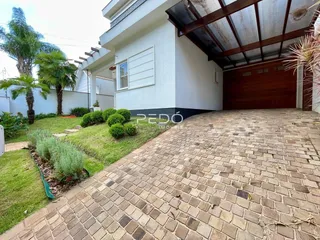 Vista da fachada de uma casa com jardim e calçada de tijolos.
