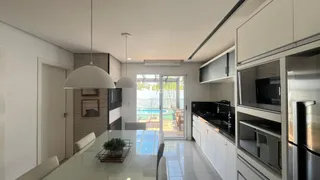 Cozinha moderna com ilha e acesso a uma área externa com piscina.