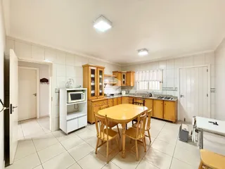 Sala de jantar com mesa de madeira e cozinha em um imóvel.