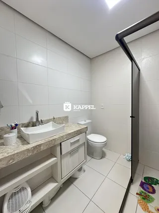 Banheiro com bancada de granito e vaso sanitário branco.