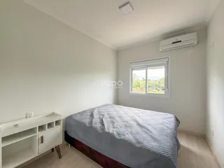 Quarto com cama e móveis brancos em um imóvel.