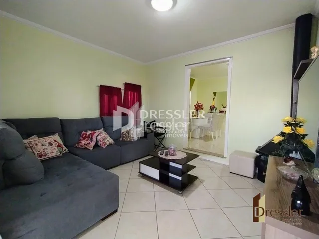 Sala de estar com sofá cinza e paredes verdes.