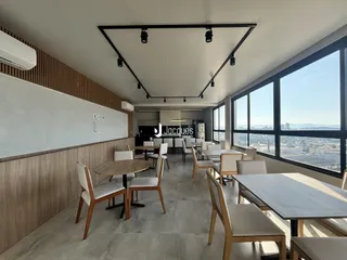 Ambiente interno com mesas e vista panorâmica da cidade.