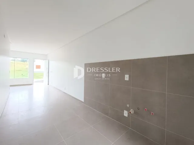 Corredor interno de uma residência com piso claro e paredes brancas.