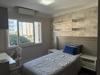 Quarto com cama e janela mostrando a vista externa da cidade.
