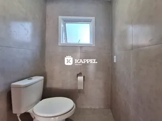 Foto de um banheiro com paredes de azulejo claro e uma janela.