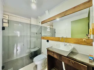 Foto de um banheiro com box de vidro e bancada de madeira.