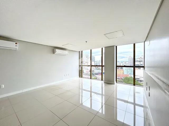 Sala de estar com piso de cerâmica e grandes janelas que oferecem vista da cidade.