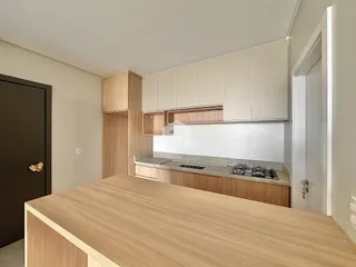 Vista da cozinha com armários de madeira clara e bancada moderna.