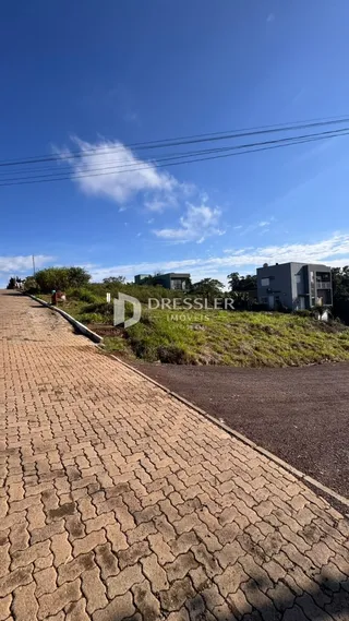 Vista da rua e paisagem com uma residência ao fundo.