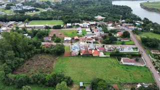 Vista aérea de uma propriedade rural com vegetação densa e corpo d'água ao fundo.