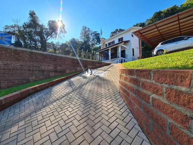 Vista da entrada de uma propriedade com muros de tijolo e calçada pavimentada.