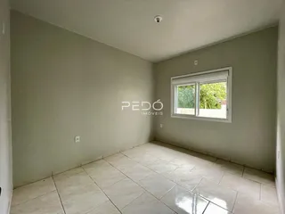 Foto de um cômodo interno com piso de cerâmica clara e parede lisa.