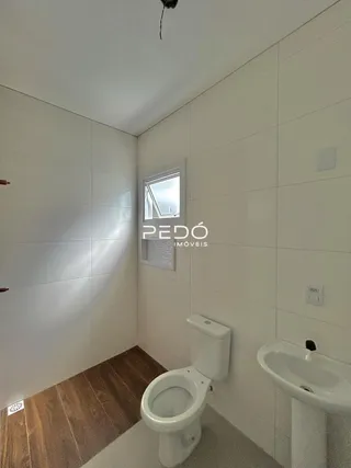 Foto de um banheiro interno com piso de madeira e paredes brancas azulejadas.