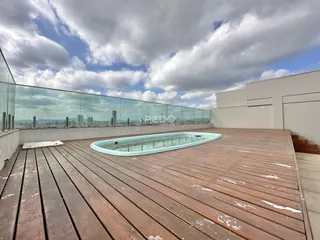 Deck de madeira com piscina e vista panorâmica da cidade.