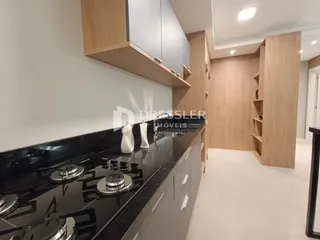 Uma cozinha moderna com armários de madeira e bancada escura.