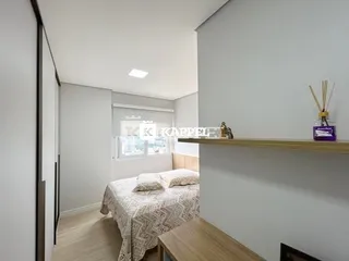 Quarto com cama e prateleira de madeira em um ambiente claro.