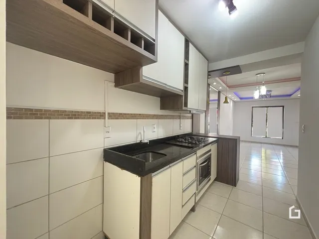 Foto da cozinha com armários brancos e revestimento de tijolos.