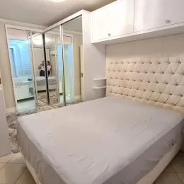 Quarto com cama de casal e cabeceira estofada branca.