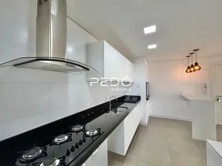 Cozinha moderna com armários brancos e bancada preta.