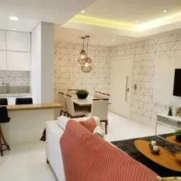 Sala de estar moderna com sofá e parede texturizada clara.