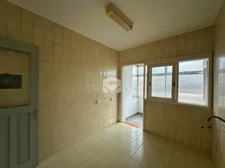 Interior de um cômodo com paredes de azulejo claro e piso de cerâmica.