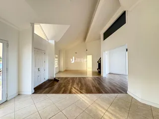 Sala de estar ampla com piso de madeira clara e paredes brancas.