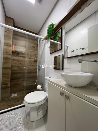 Banheiro moderno com box de vidro e louças brancas.