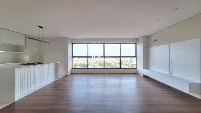 Sala de estar ampla com piso de madeira e grande janela.
