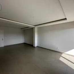 Ambiente interno amplo com paredes brancas e piso cinza.