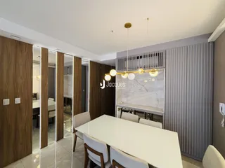 A sala de jantar apresenta uma mesa grande com cadeiras brancas em um ambiente moderno.