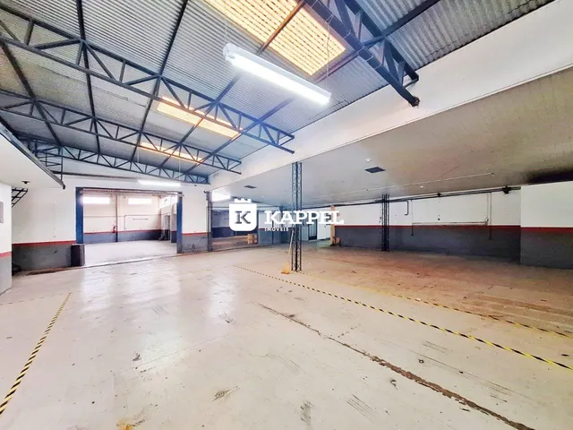 Espaço industrial amplo com estrutura de vigas metálicas e piso de concreto.