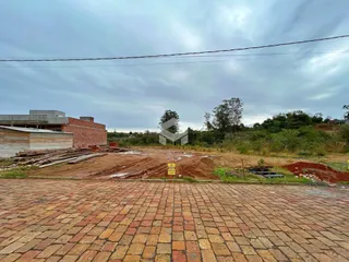 Foto da frente de um terreno com área pavimentada e terra.