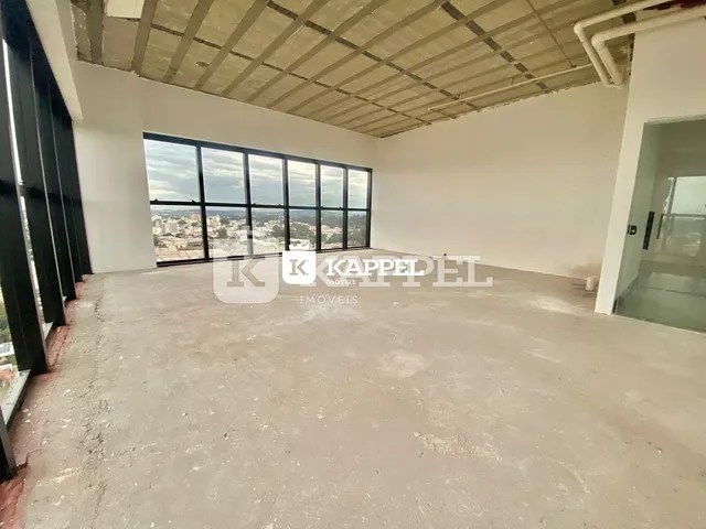 Foto de um cômodo amplo com piso de concreto e grandes janelas que oferecem uma vista panorâmica.