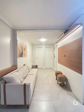 Sala de estar clara com sofá e parede de madeira no interior da residência.