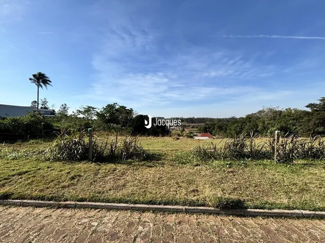 Vista externa de um terreno com vegetação rasteira e céu azul.