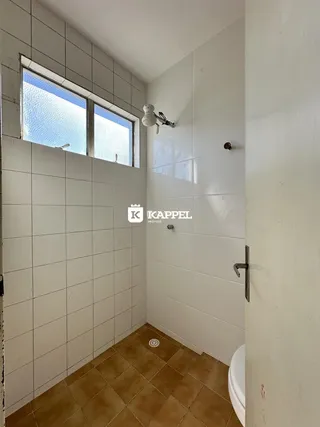 Banheiro com revestimento de azulejos brancos e piso de terracota.