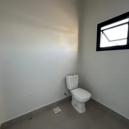Foto de um ambiente interno mostrando um vaso sanitário e uma parede branca.