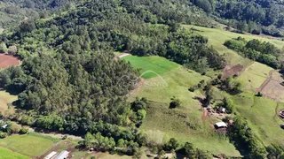 Vista aérea de uma área rural com vegetação densa e campos verdes.