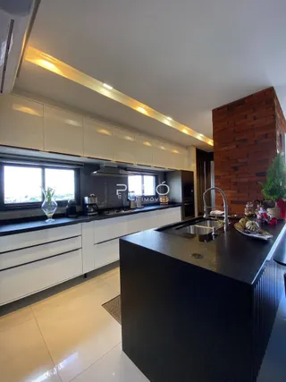 Cozinha moderna com armários brancos e bancada escura.