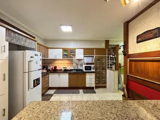 Foto de uma cozinha aberta com armários e eletrodomésticos brancos.