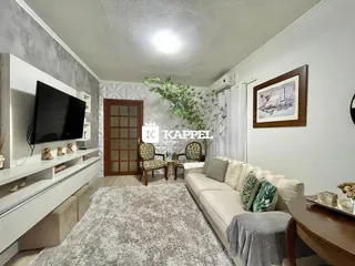 Sala de estar com sofá e televisão em um ambiente claro.