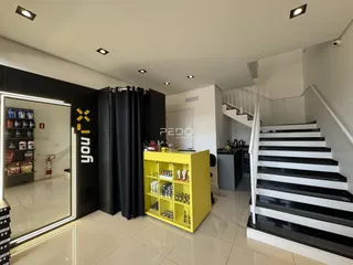 Interior de uma sala com cortinas escuras e um corredor de acesso a uma escada.