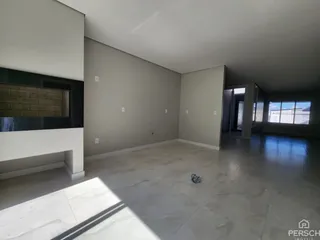 Uma sala ampla e vazia com piso claro e paredes cinzas.