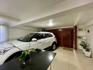 Interior de uma sala com um carro branco estacionado.