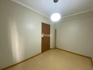 Foto de um cômodo interno com paredes brancas e piso de madeira clara.