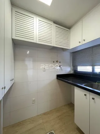 Foto de uma cozinha com armários brancos e bancada escura.