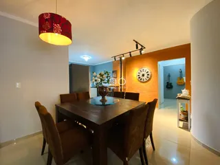 Foto de uma sala de jantar com mesa de madeira escura e ambiente claro.